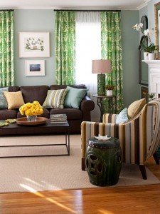 A living room with vibrant green curtains and earth-toned brown furniture.