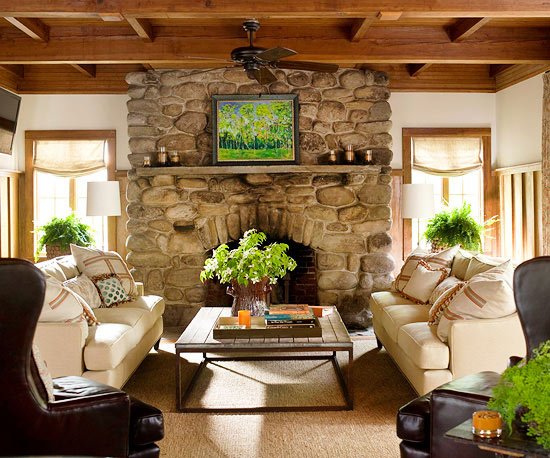 A cozy living room with colorful couches and a stone fireplace.