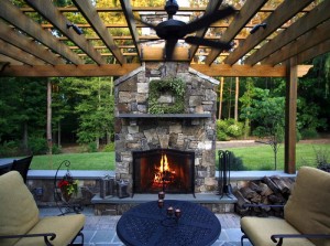 An outdoor living space with a stone fireplace and patio furniture.