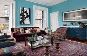 A living room with blue walls and a colorful rug showcasing patterns.