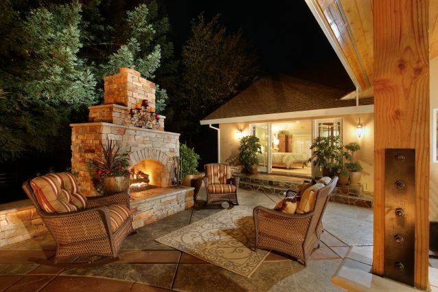 Outdoor living space equipped with a stone fireplace and wicker furniture.