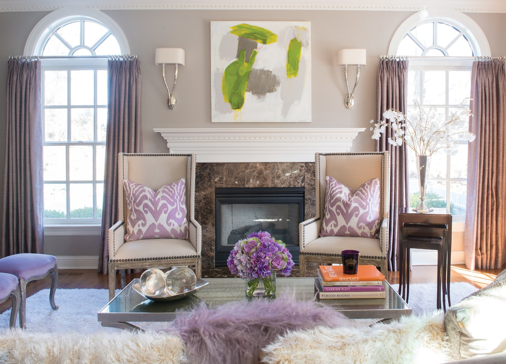 A living room with purple and white furniture, decorated with pastels and featuring a fireplace.