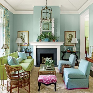 A living room with blue walls and green furniture decorated with pastels.