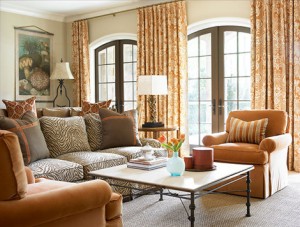 A living room with a animal print couch, chairs and a coffee table.