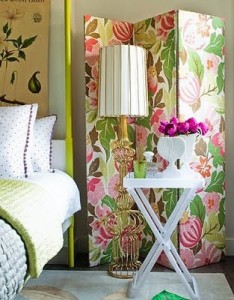 A bedroom with floral wallpaper and folding screens.