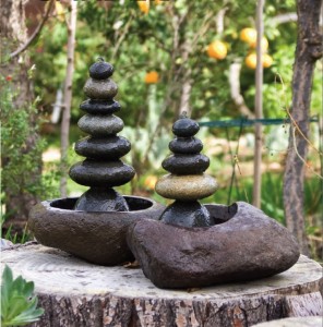 Two stacks of rocks on top of a stump in a backyard garden.