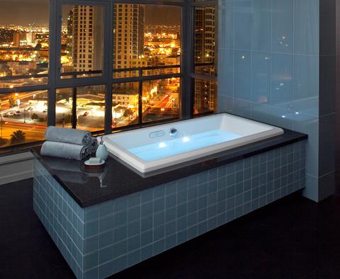 A bathroom with a view of a city at night.