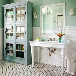 A cottage-style bathroom with green walls and white cabinets.