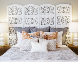 A bed with pillows and a headboard featuring folding screens.