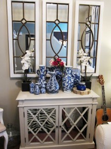 A white and blue dresser with vases and a guitar can be used for decorating with mirrors.