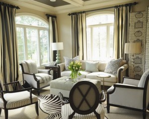 A living room with black and white furniture and zebra print curtains featuring animal prints.