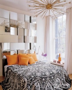 A bedroom with orange and white bed, decorated with mirrors.