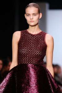 A model wearing a burgundy dress showcasing color combinations on the runway.