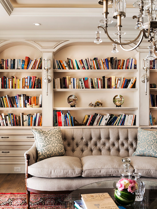 A living room with bookshelves and a chandelier designed for impressive lighting.
