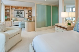 A master bedroom with a white bed and a white dresser.