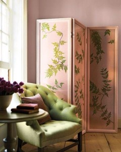 A room with pink walls, a green chair, and folding screens.