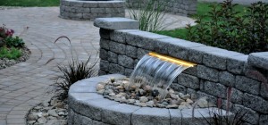 A backyard water feature with a stone wall.