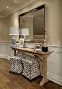A space-saving entryway table with a mirror and two ottomans.