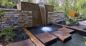 Backyard water feature with stone wall.