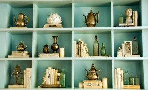 A shelf decorated with books and vases in blue color.