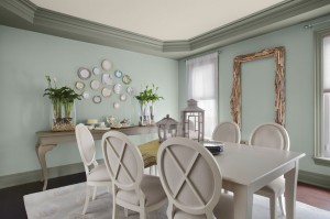 A dining room with white furniture and green walls.