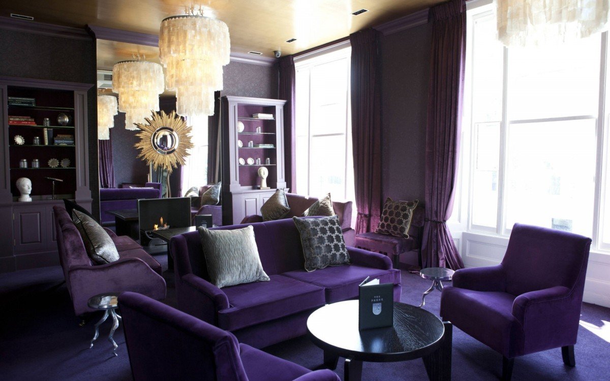 A living room with purple furniture and a chandelier, decorated with purple accents.