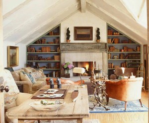 A rustic living room with a fireplace and bookshelves.