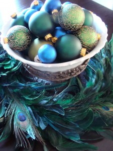 Peacock feathers and Christmas ornaments in a bowl, perfect for decorating with birds during the holiday season.