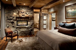 A stone fireplace enhances a rustic bedroom.