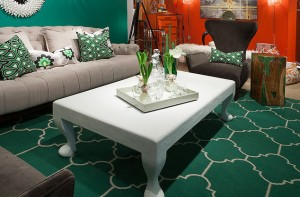 A living room with a green and white rug, decorated with green accents.