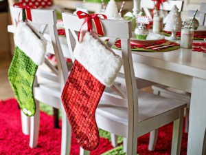 Festive Christmas stockings hanging on chairs in a dining room.