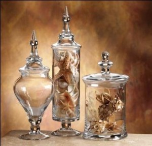 Three decorative glass jars filled with sea shells.