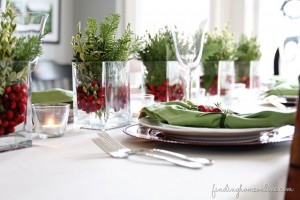 A festive Christmas table setting featuring cranberries and greenery.
