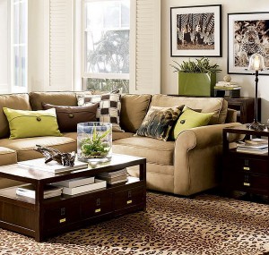 A living room with a leopard print couch and coffee table, decorated with green accents.
