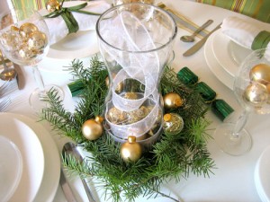 Festive Christmas table setting with gold ornaments and greenery.