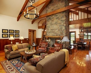 A rustic living room with wood beams and a stone fireplace.