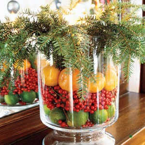A festive glass vase filled with oranges and berries for decorating the holiday table.