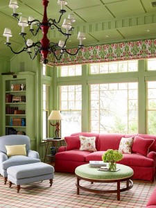 A living room with green walls decorated with red furniture.