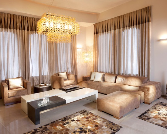 A living room with beige furniture and a crystal chandelier.