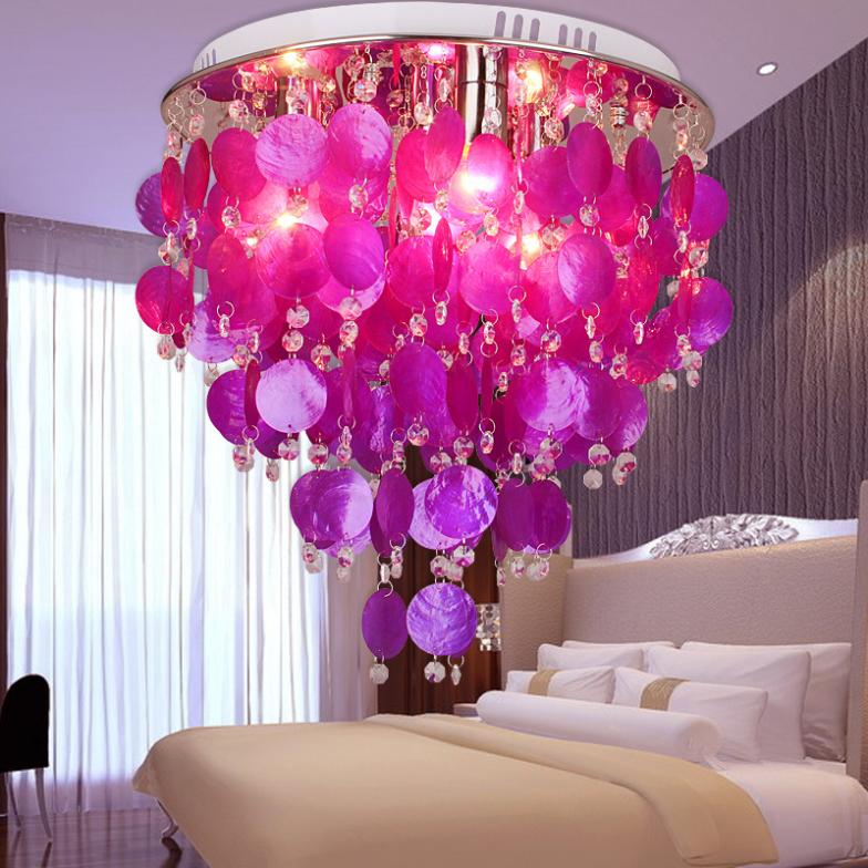 A romantic bedroom with a purple chandelier hanging over a bed.