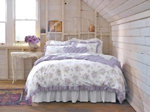 A shabby chic bedroom with a white and purple bed and pillows.