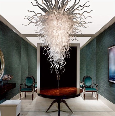 Shimmering crystal chandelier hangs over a dining room table.