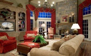 A living room with red velvet furniture and a fireplace.