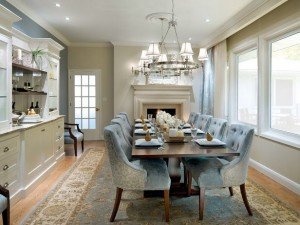A formal dining room with velvet blue chairs and a fireplace.