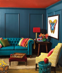 A living room with bold blue walls and vibrant furniture.