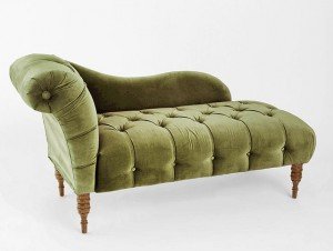 A green velvet chaise lounge with wooden legs.