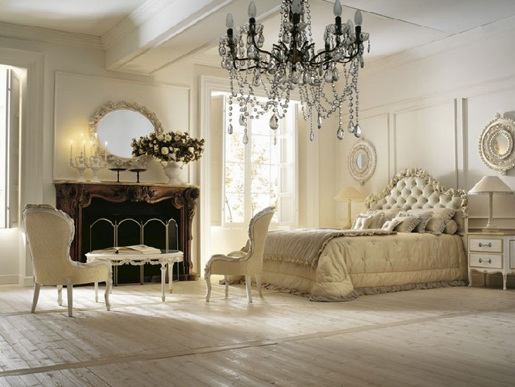 A romantic bedroom with white furniture and a chandelier.