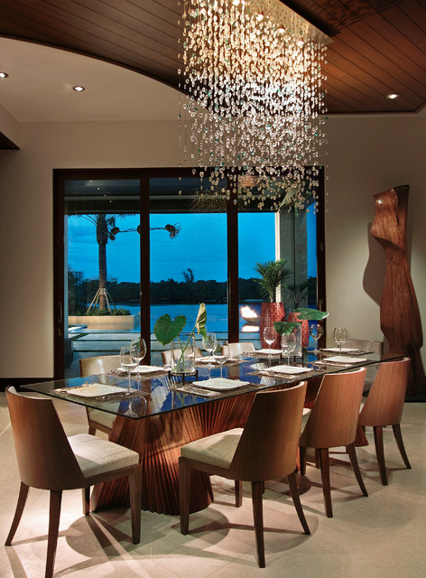 A dining room with a large shimmering glass table and chairs.