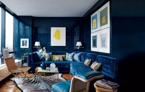 A living room with a blue velvet couch and zebra rug.