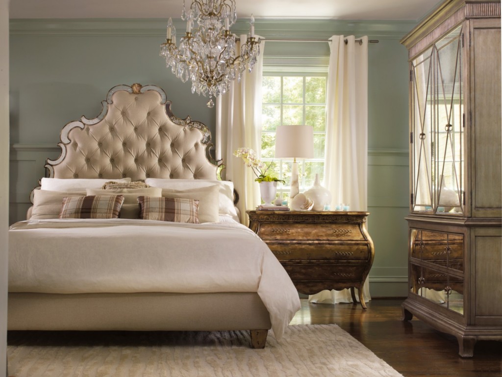 A romantic bedroom with a bed, dresser, and a chandelier.